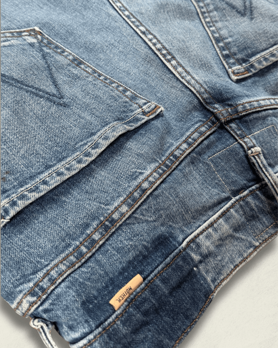 MOTHER Mid-Rise Maven Ankle wide-leg jean in medium blue denim with a raw frayed hem and crown-stitch back pockets, shown flat.