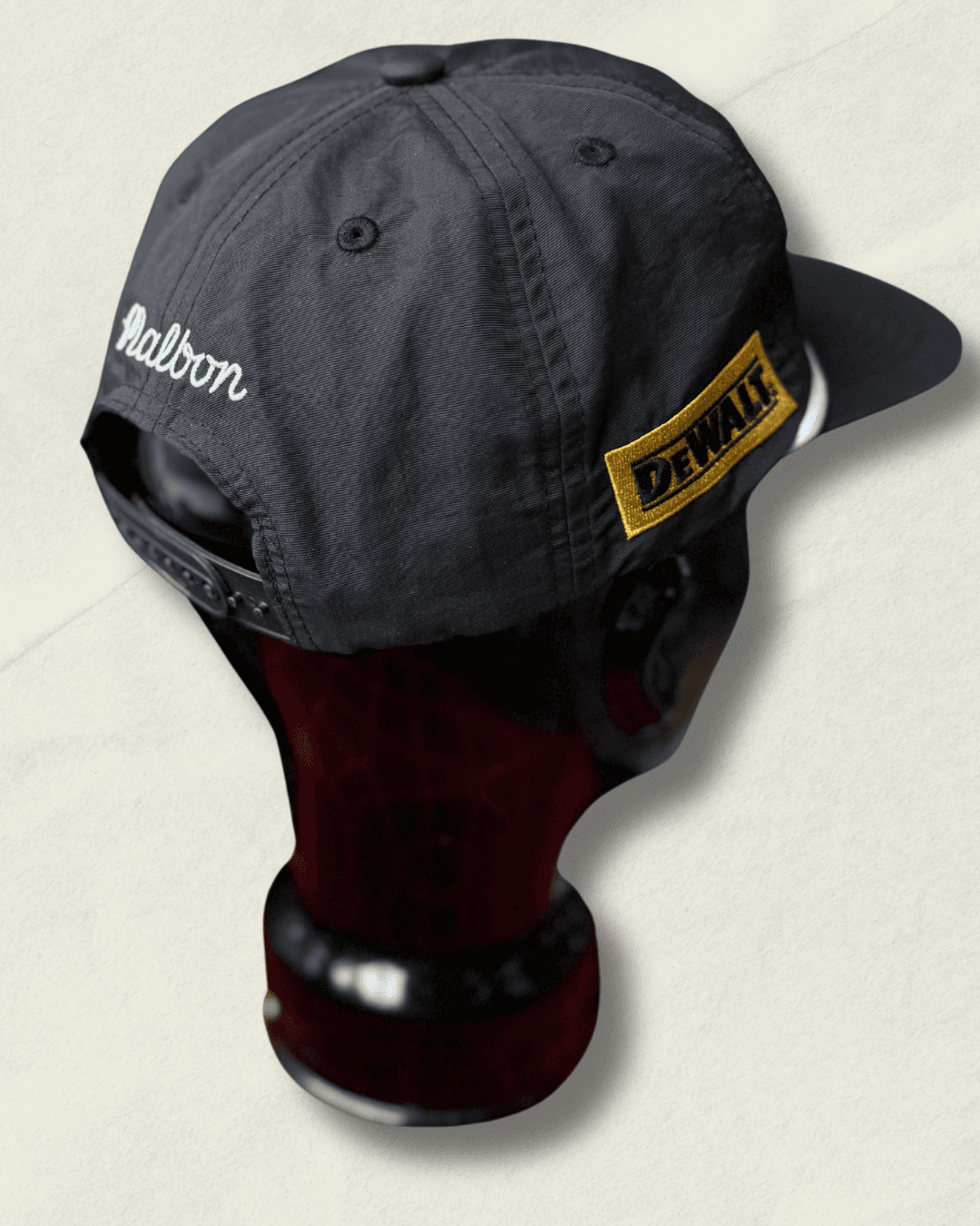 Black Malbon Golf x Motive x DeWalt nylon rope golf hat, front view with raised white motive embroidery, white rope, and yellow DeWalt patches on the sides.