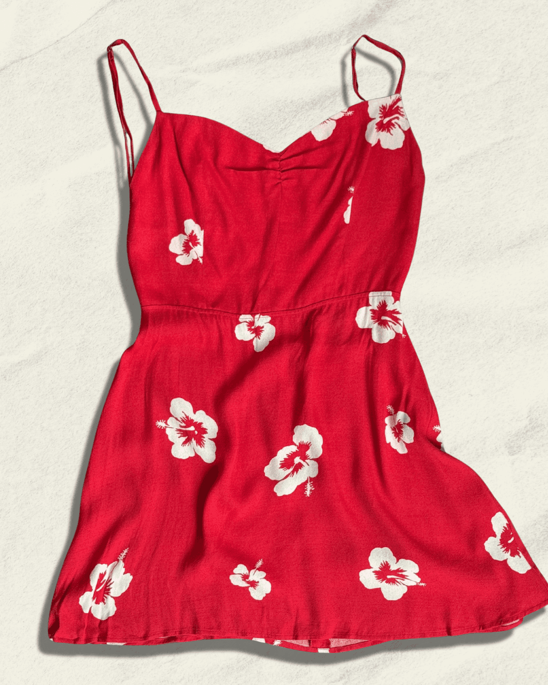 Reformation Junebug mini dress in the Honolulu print, true red with white hibiscus flowers, sweetheart neckline and thin adjustable straps, shown flat.
