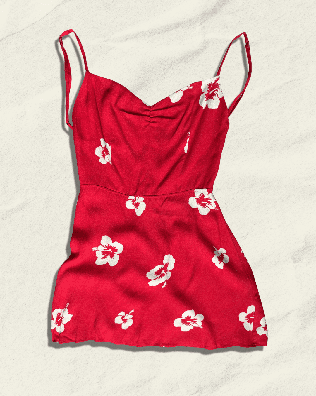 Reformation Junebug mini dress in the Honolulu print, true red with white hibiscus flowers, sweetheart neckline and thin adjustable straps, shown flat.