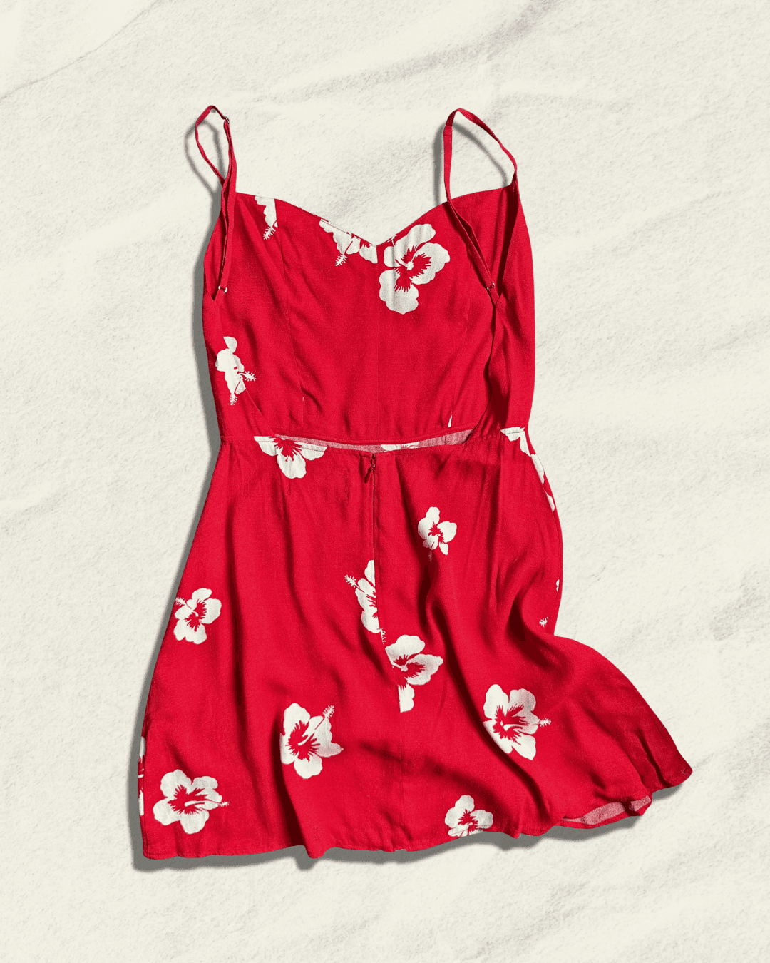Reformation Junebug mini dress in the Honolulu print, true red with white hibiscus flowers, sweetheart neckline and thin adjustable straps, shown flat.