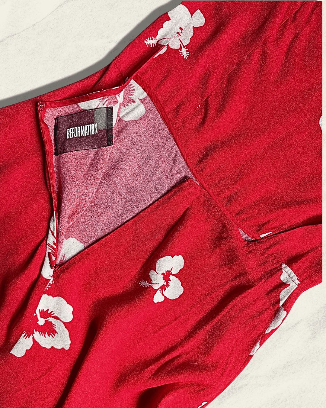 Reformation Junebug mini dress in the Honolulu print, true red with white hibiscus flowers, sweetheart neckline and thin adjustable straps, shown flat.