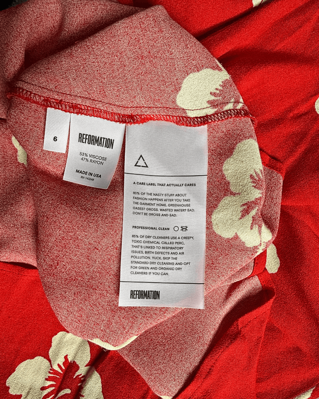 Reformation Junebug mini dress in the Honolulu print, true red with white hibiscus flowers, sweetheart neckline and thin adjustable straps, shown flat.