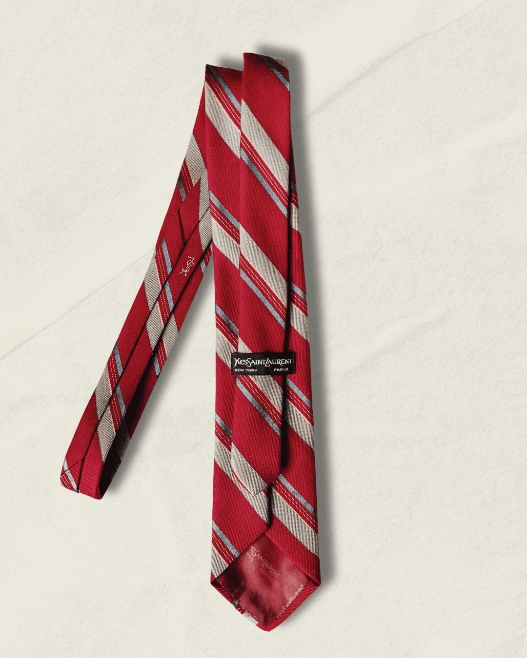 Vintage Yves Saint Laurent crimson repp-stripe tie with sand and sky-blue diagonal stripes, styled over a blue gingham shirt and houndstooth jacket.