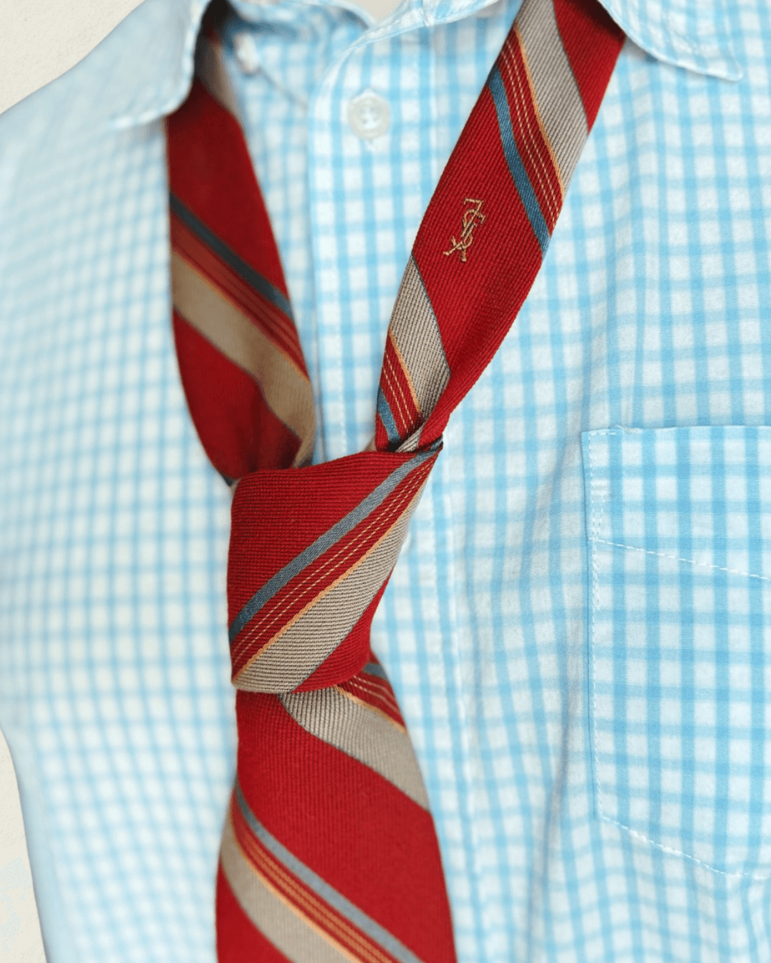 Vintage Yves Saint Laurent crimson repp-stripe tie with sand and sky-blue diagonal stripes, styled over a blue gingham shirt and houndstooth jacket.